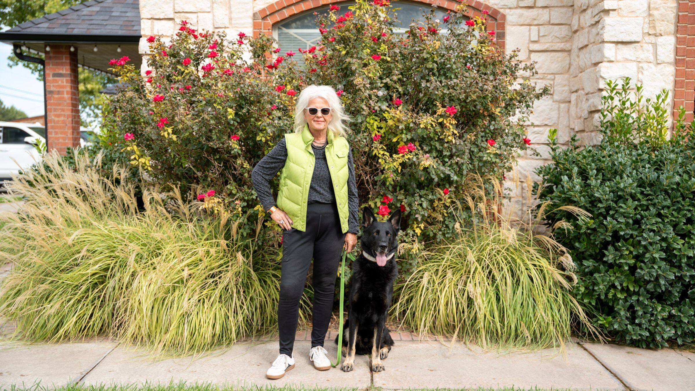 Lisa Price standing outdoors with a black shepherd